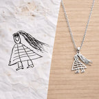 Collier personnalisé en acier inoxydable inspiré d’un dessin d’enfant, sur fond bois.