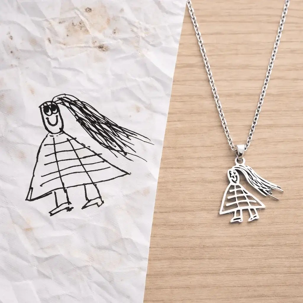 Collier personnalisé en acier inoxydable inspiré d’un dessin d’enfant, sur fond bois.
